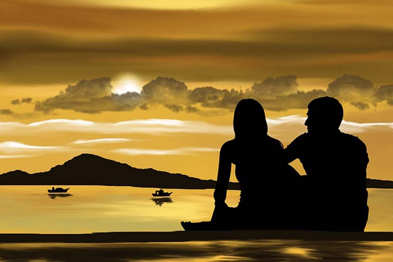 couple sit on bech looking at sunset