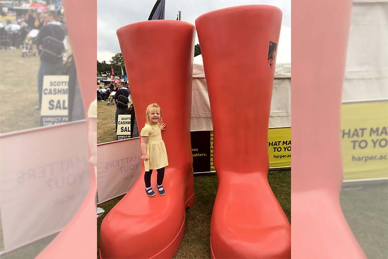child standing on giant red wellies