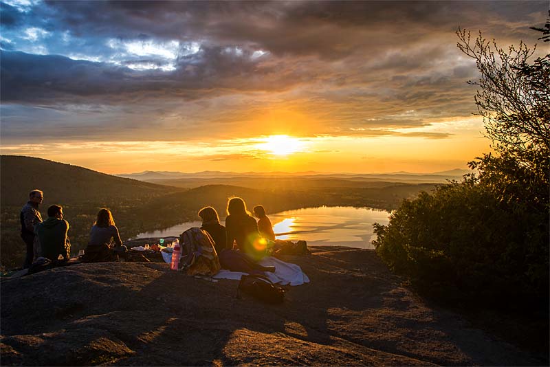 friends watch sunset from hilltop
