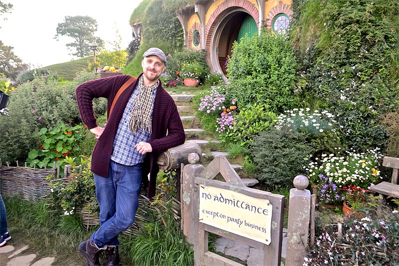 kyle pedley stands outside a replica hobbit house