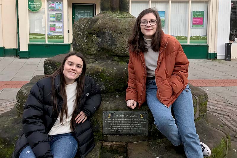 two people sit by buttercross in newport