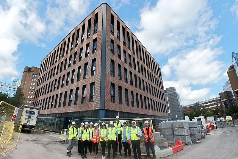 trust leaders stadn outside of the new quad building